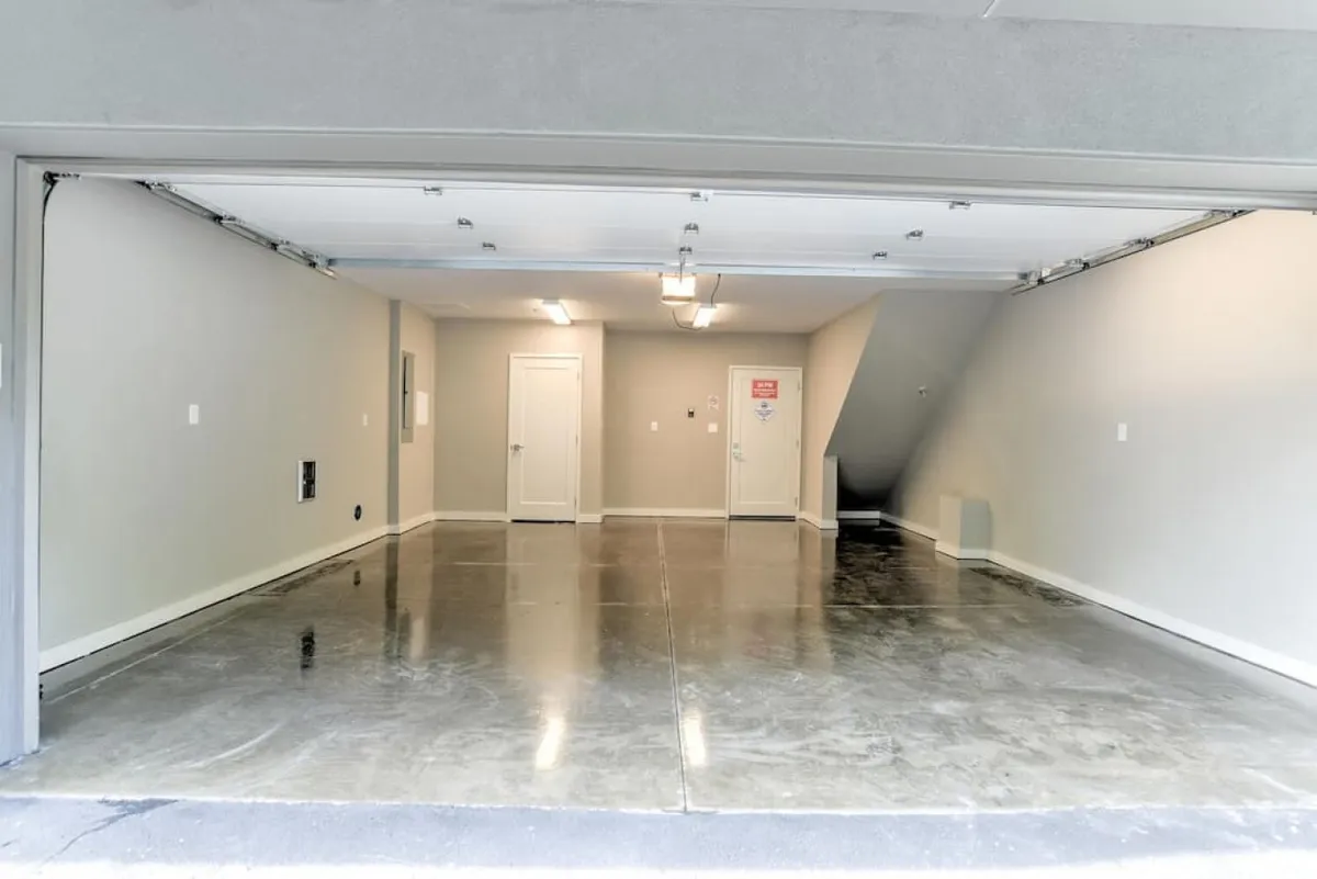A spacious, empty garage with clean white walls, ample lighting, and a functional layout. The space is uncluttered, highlighting its utility for parking vehicles and offering secure, private entry to the home.