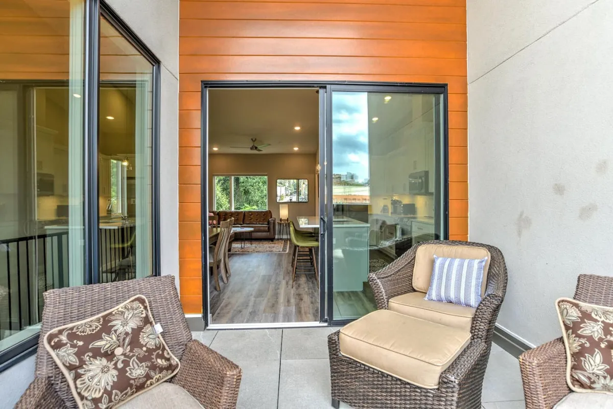 A welcoming patio with comfortable seating, glass sliding doors connecting the exterior to the interior dining area. The patio is set for relaxation or socializing, hinting at moments of unwinding after a day in the city while enjoying sunset views.
