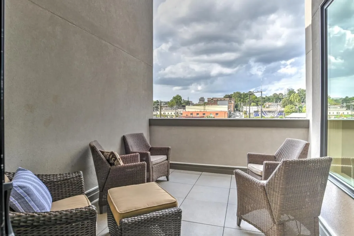 A tranquil rooftop terrace set with wicker chairs and a small ottoman, offering a panoramic view of the cityscape. The space is perfect for relaxing, hosting small groups, or simply soaking in Asheville’s skyline, especially at sunset.